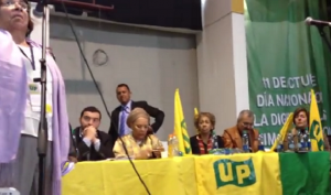 Andrés Villamizar Pachón, director de la Unidad Nacional de Protección, ovacionando a Aida Avella en una reunión política de la UP en noviembre de 2013, y pidiendo un "frente común contra los enemigos de la paz"
